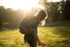 Child being carried by another, out in nature