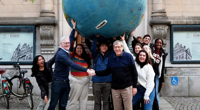 students and teachers with large ball in front of building