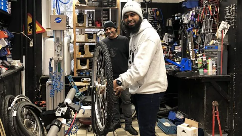 Two men repairing a bike in a bike shop. Photo. 