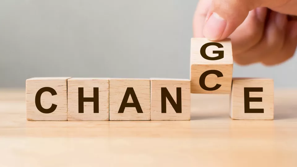 Cubes forming the word change but a hand is turning the cube with the letter G and makes it form the word Chance instead. Photo. 