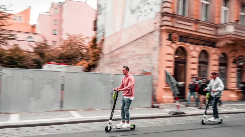 Two guys on electric scooters in a city. Photo. 