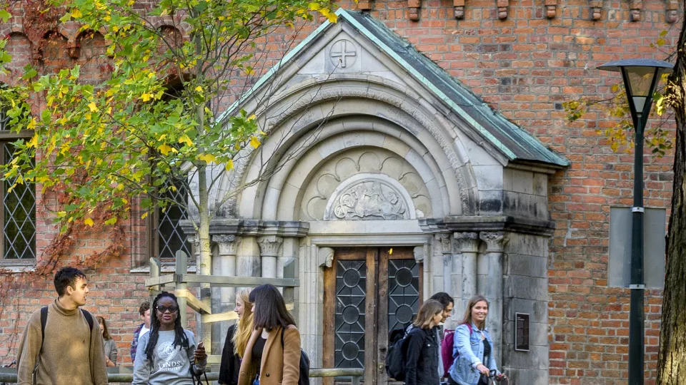 Student walking in front of an old building in the autumn. Photo. 