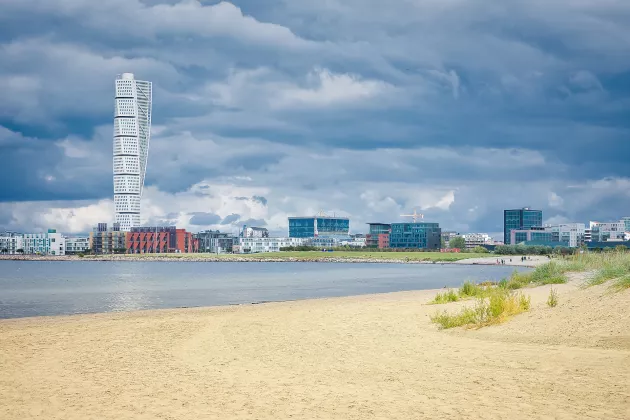 The beach at Ribersborg with the skyline of the Western harbour and turning turso and a cloudy sky. Photo.