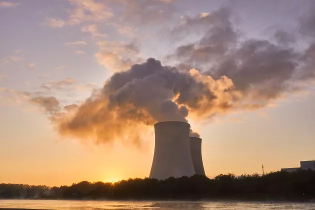 Nuclear power plant with smoke and sunset behind. Photo. 