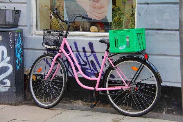 A pink bike parked on the sidewalk