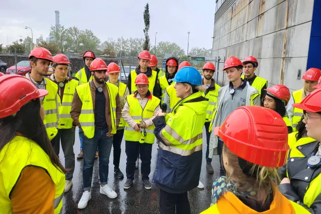 A group of visitors in yellow vests outside a building