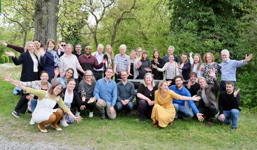 Group photo of the staff. Taken outside with trees behind. Photo. 