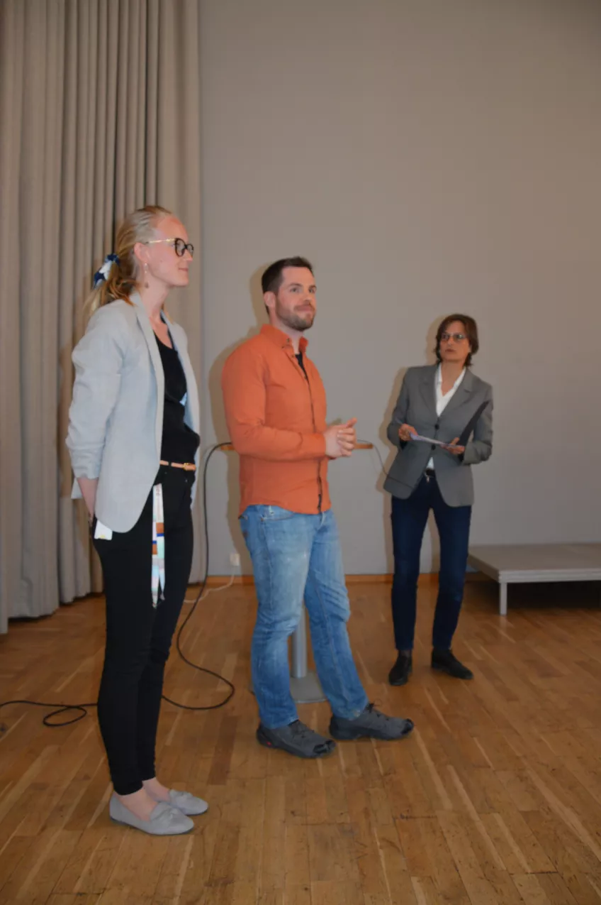 Sofie Sandin Lompar, Steven Curtis and Kristina Jönsson standing with a wall and curtain behind them. Photo. 